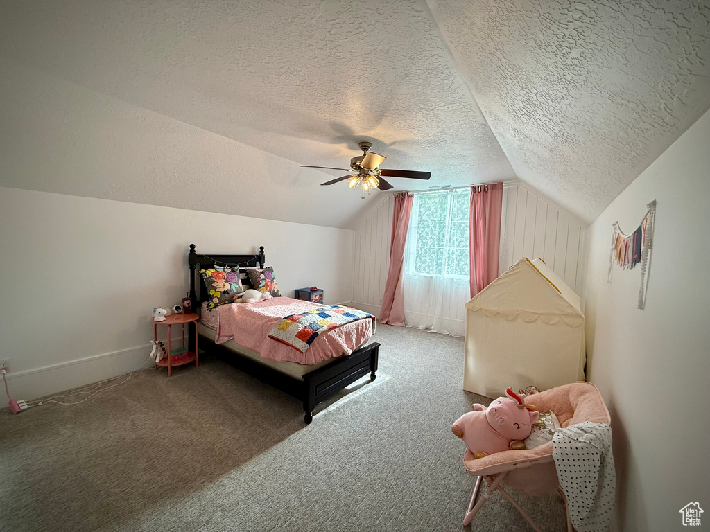 Bedroom with a textured ceiling, vaulted ceiling, carpet, ceiling fan, and baseboards