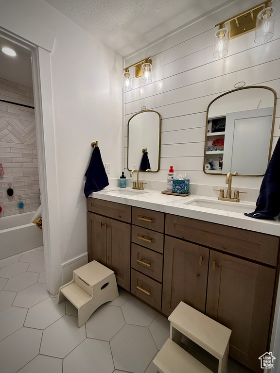 Bathroom with double vanity, tile patterned flooring, and shower / bath combination