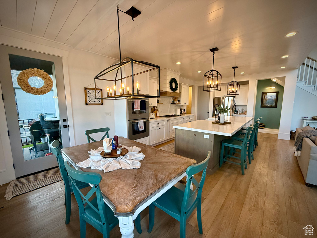 Dining area with a chandelier, light wood-style flooring, stairs, and recessed lighting