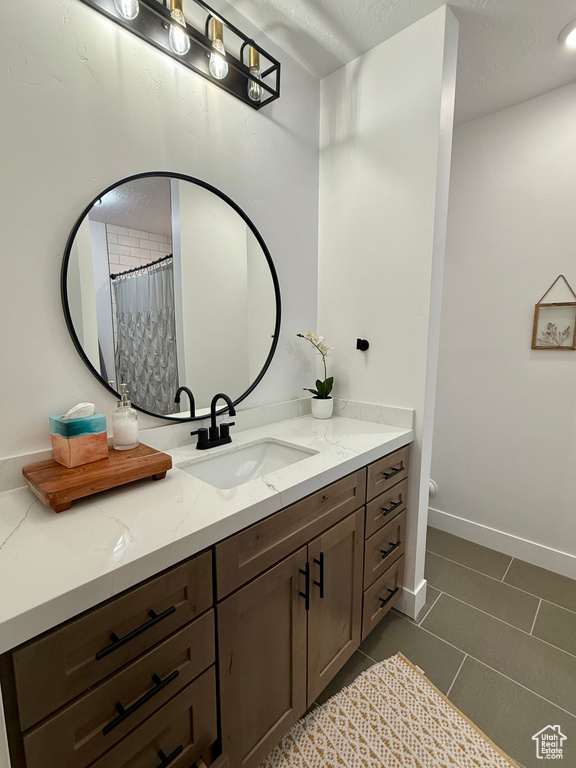 Full bathroom featuring vanity, tile patterned floors, baseboards, and a textured ceiling
