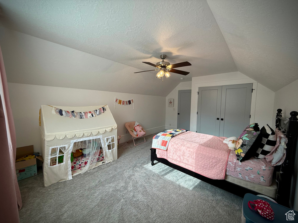 Bedroom with vaulted ceiling, carpet, a textured ceiling, and ceiling fan