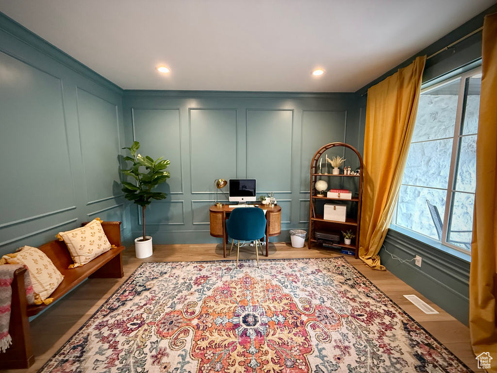 Home office featuring a decorative wall and wood finished floors