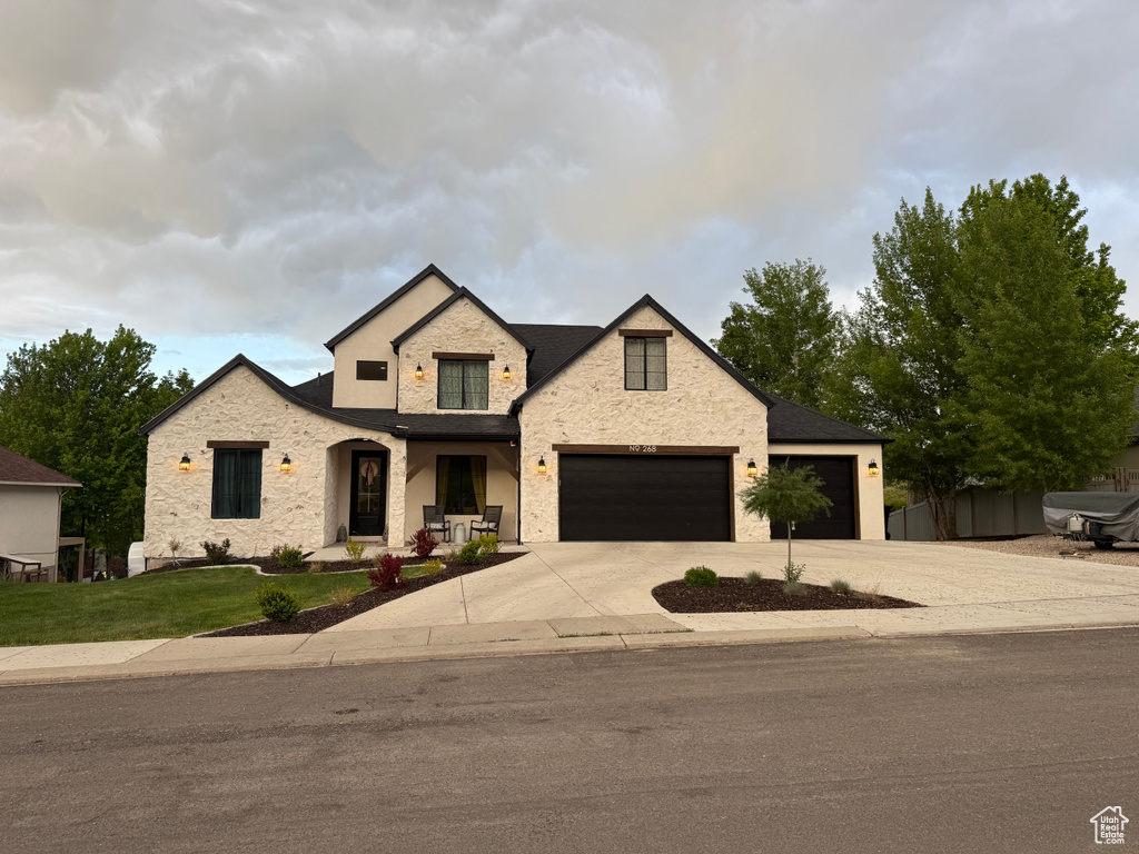 View of front of house with stone siding, driveway, an attached garage, and a front yard