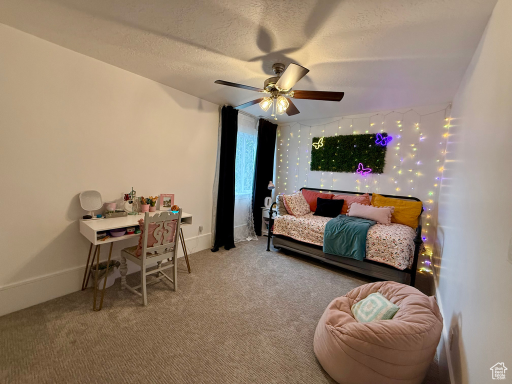 Carpeted bedroom featuring a textured ceiling, baseboards, and a ceiling fan