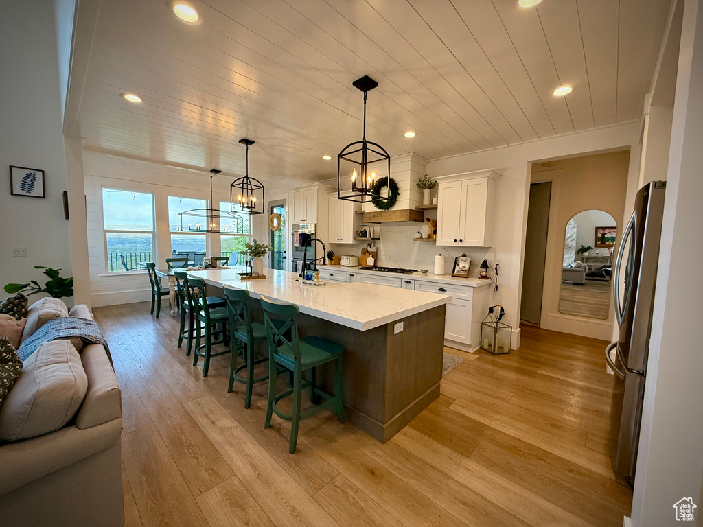 Kitchen with a chandelier, stainless steel appliances, wood ceiling, light wood finished floors, and white cabinetry