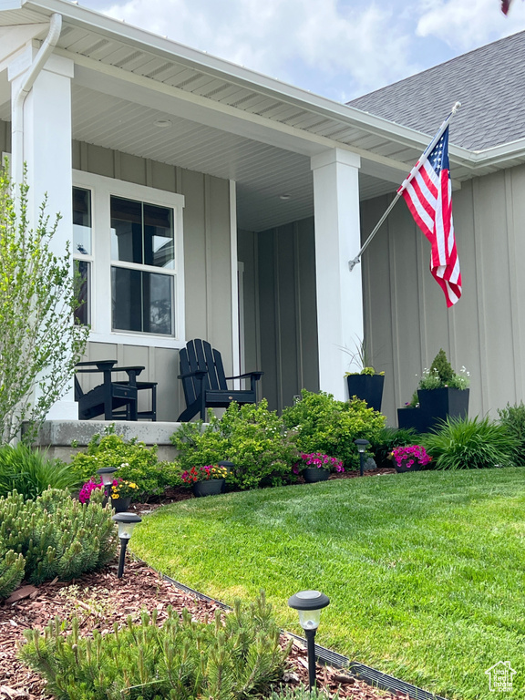 Property entrance with board and batten siding, a yard, a porch, and roof with shingles