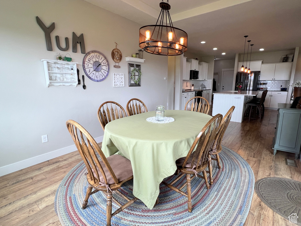 Dining area featuring a chandelier, light wood-style flooring, baseboards, and recessed lighting