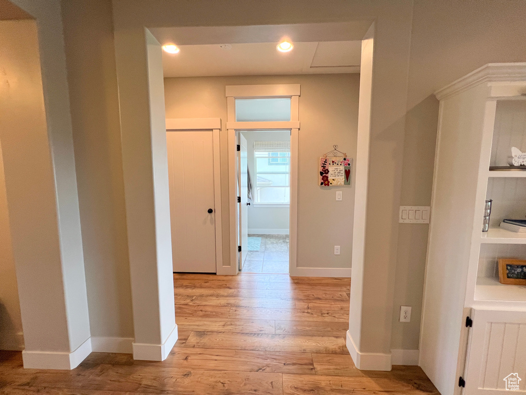 Hall with light wood finished floors, baseboards, and recessed lighting