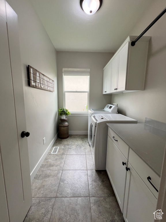 Laundry room featuring separate washer and dryer, cabinet space, and baseboards