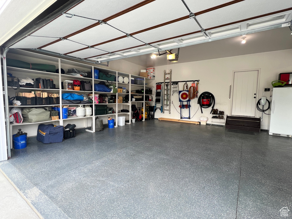 Garage featuring freestanding refrigerator and a garage door opener