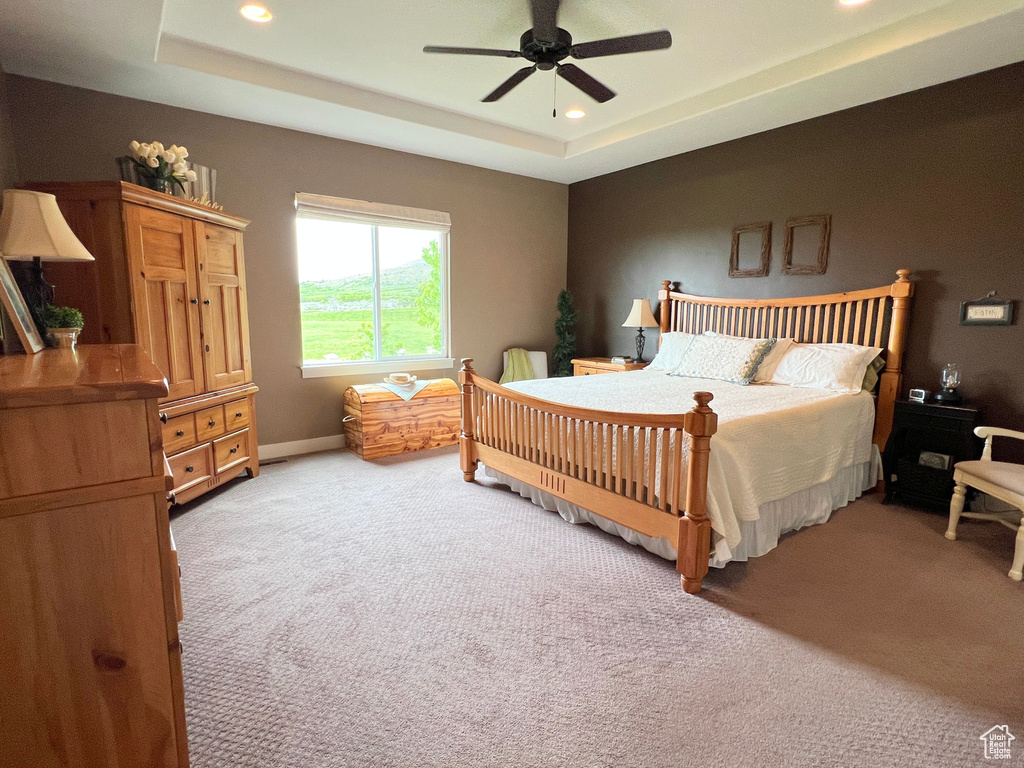 Bedroom with light colored carpet, recessed lighting, a raised ceiling, a ceiling fan, and baseboards