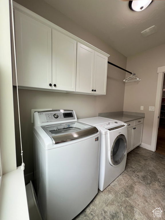 Washroom featuring independent washer and dryer, cabinet space, baseboards, and light stone finish floors