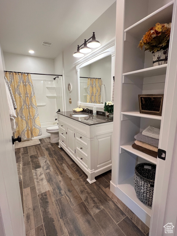 Full bathroom with wood finished floors, vanity, shower / bath combo, toilet, and recessed lighting