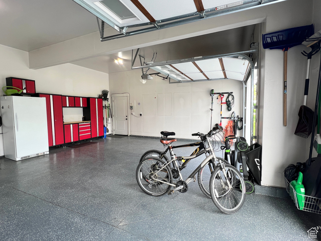 Garage featuring freestanding refrigerator and a garage door opener
