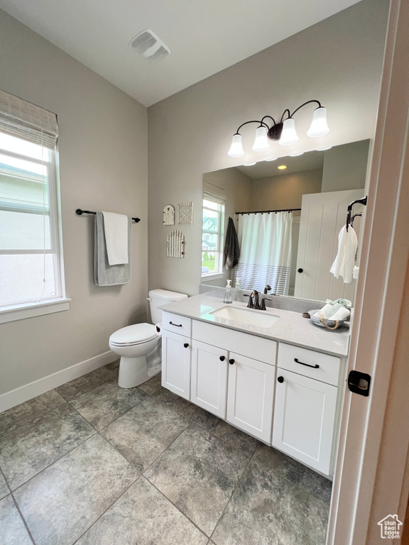 Full bathroom featuring toilet, vanity, baseboards, and curtained shower