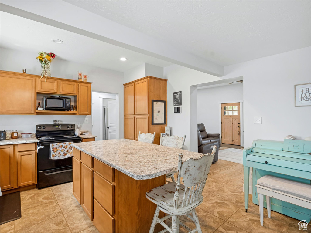 Kitchen with black appliances, a center island, light countertops, a kitchen bar, and recessed lighting
