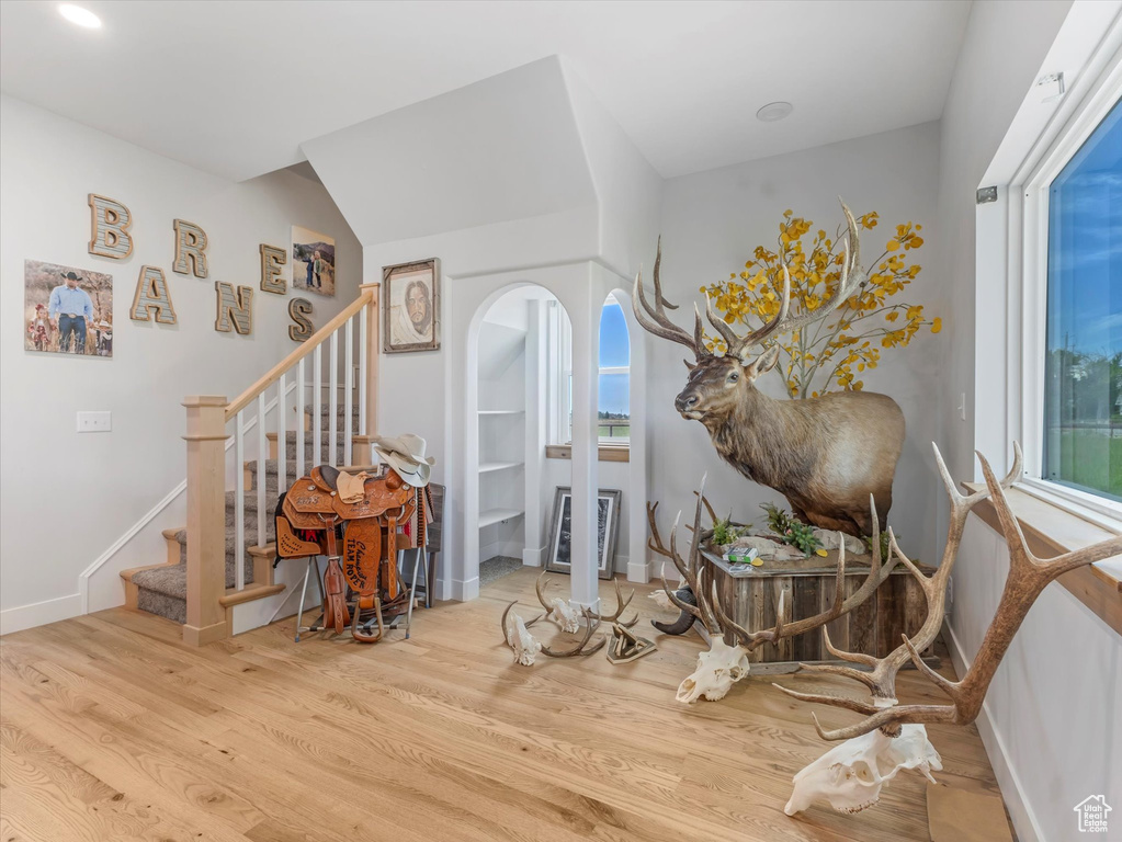 Foyer with wood finished floors, arched walkways, stairs, and baseboards