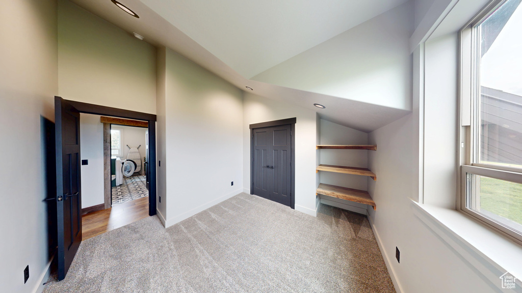 Additional living space featuring healthy amount of natural light, carpet, baseboards, and high vaulted ceiling
