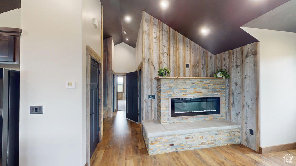 Unfurnished living room with a fireplace, wood finished floors, baseboards, and high vaulted ceiling