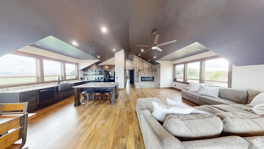 Living room featuring lofted ceiling, ceiling fan, plenty of natural light, light wood-type flooring, and a fireplace