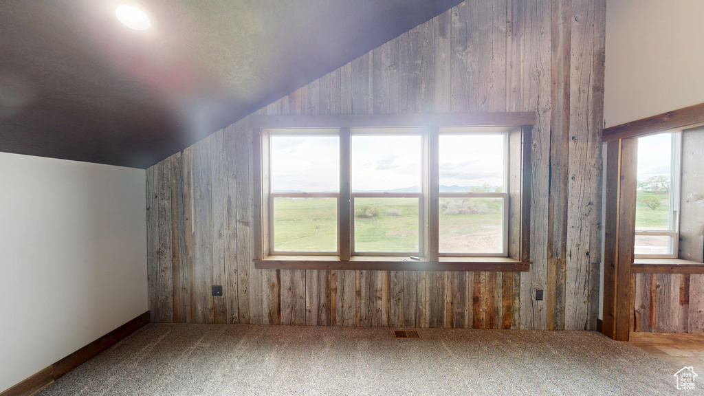 Additional living space featuring lofted ceiling, carpet flooring, and wood walls
