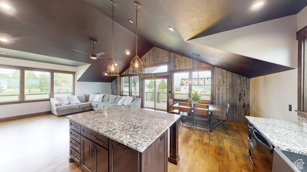 Kitchen featuring a ceiling fan, light wood-style flooring, dishwasher, hanging light fixtures, and light stone countertops