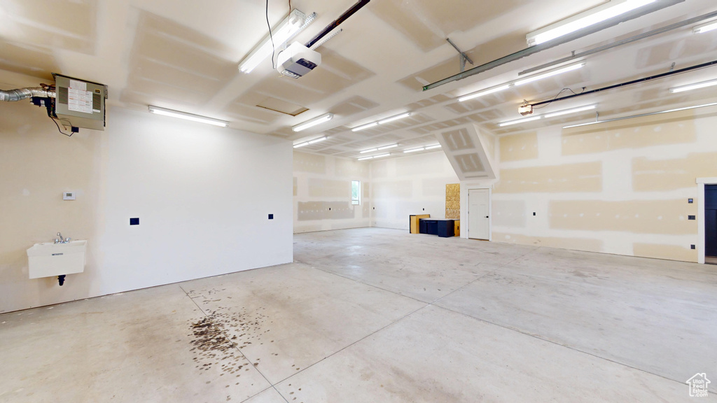 Garage with a garage door opener, a sink, and a heating unit