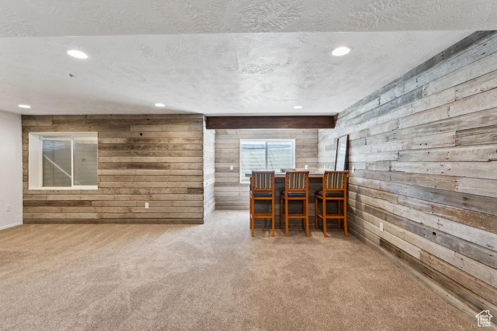 Carpeted dining area featuring wooden walls, recessed lighting, and a textured ceiling