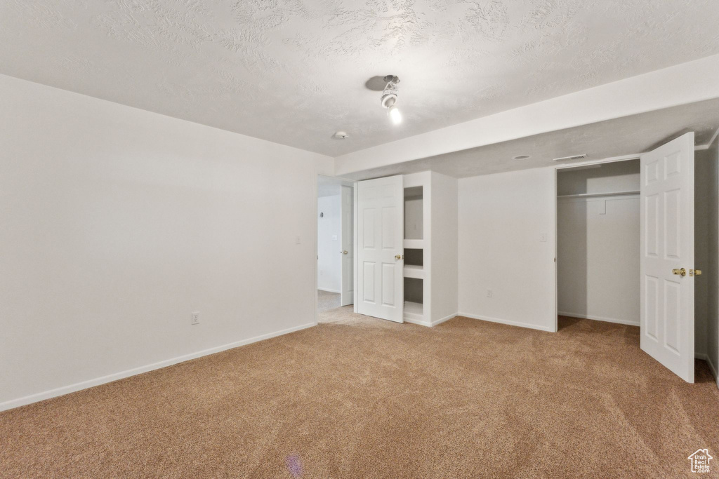 Unfurnished bedroom with carpet floors, baseboards, a textured ceiling, and a closet