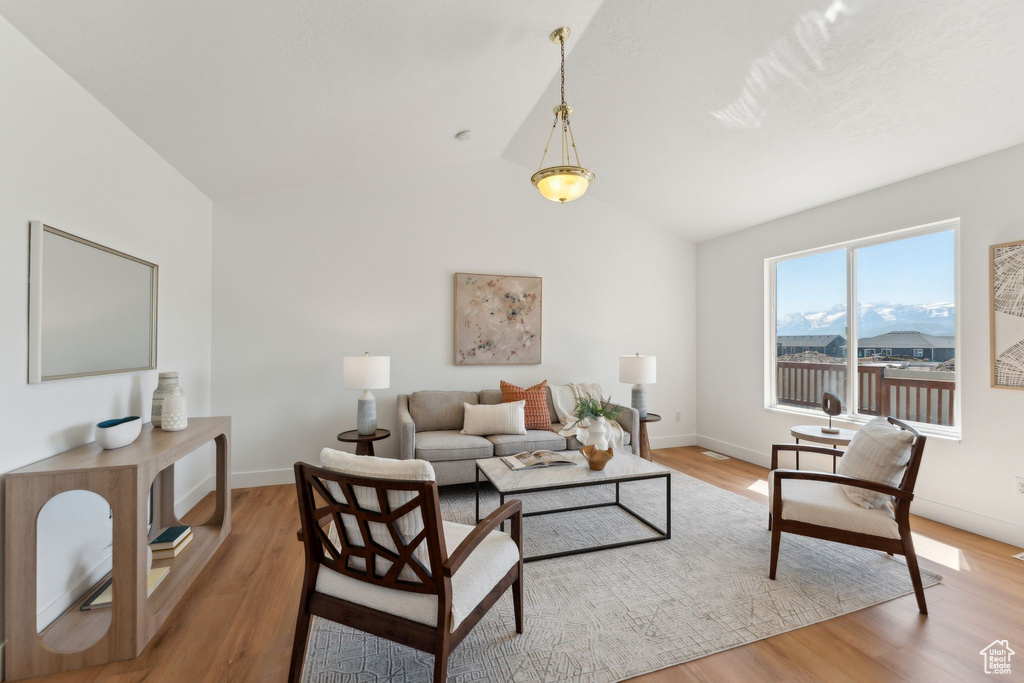 Living room with light wood-type flooring, vaulted ceiling, and baseboards