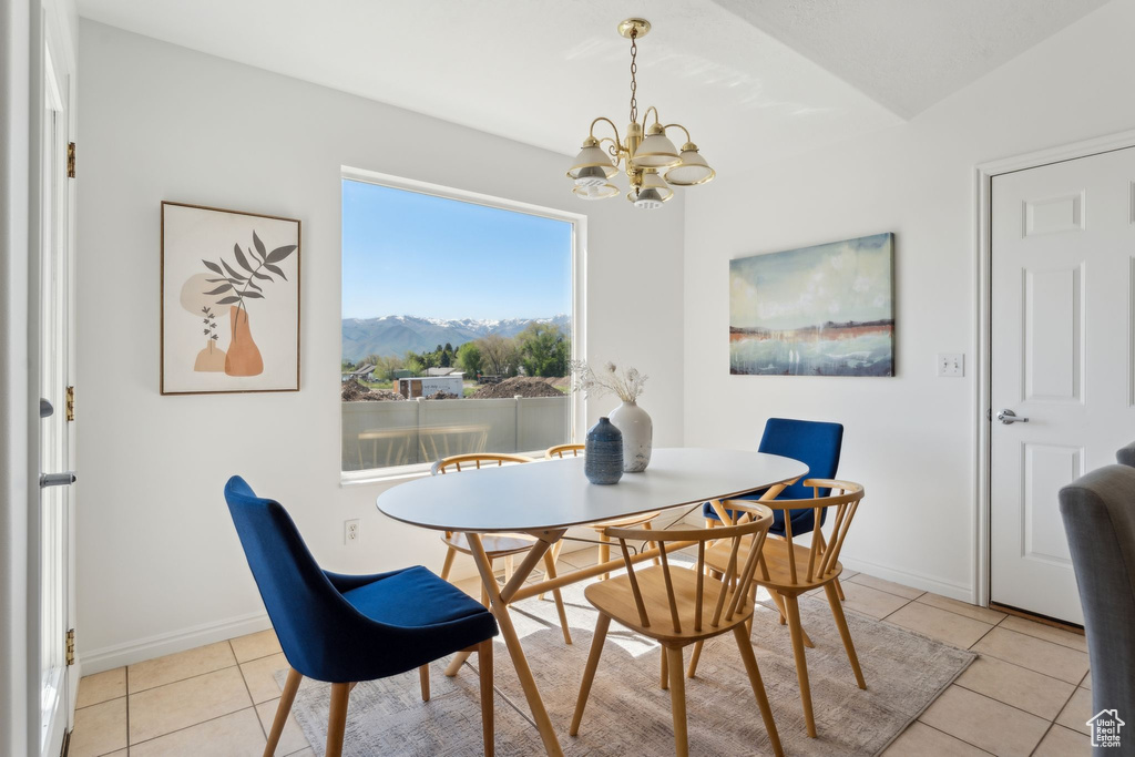 Dining space with light tile patterned flooring, a chandelier, a mountain view, and baseboards