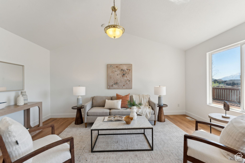 Living area with wood finished floors, lofted ceiling, and baseboards