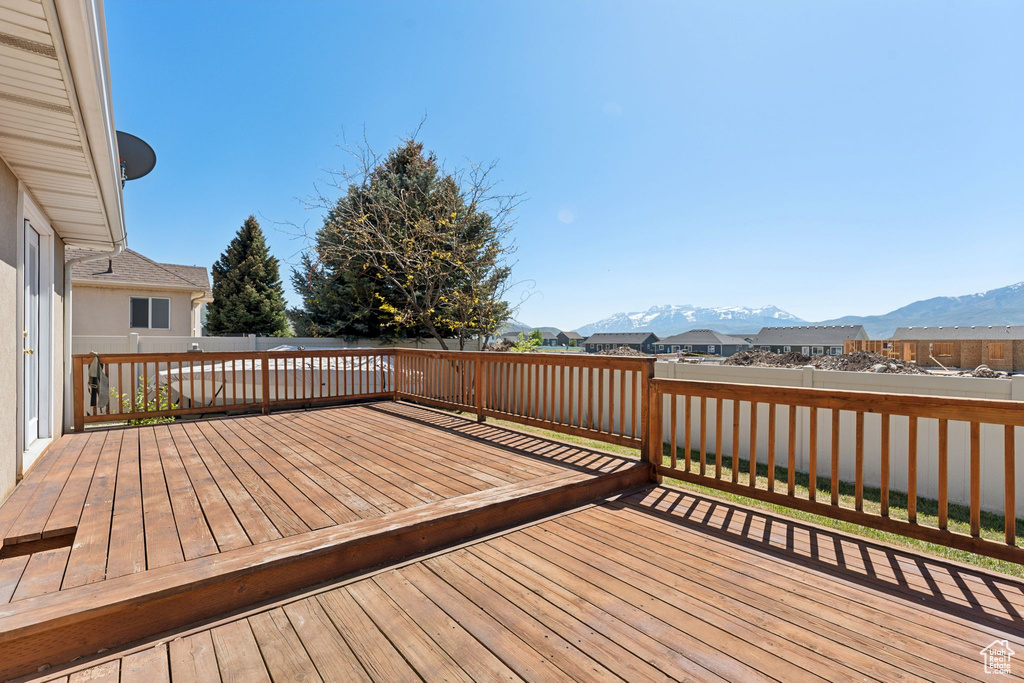 Wooden terrace featuring a mountain view, a fenced backyard, and a residential view