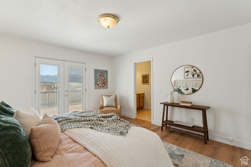 Bedroom featuring french doors, access to exterior, light wood finished floors, and baseboards