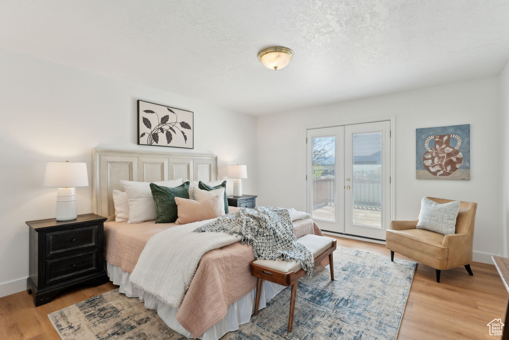 Bedroom with access to outside, french doors, light wood-type flooring, baseboards, and a textured ceiling