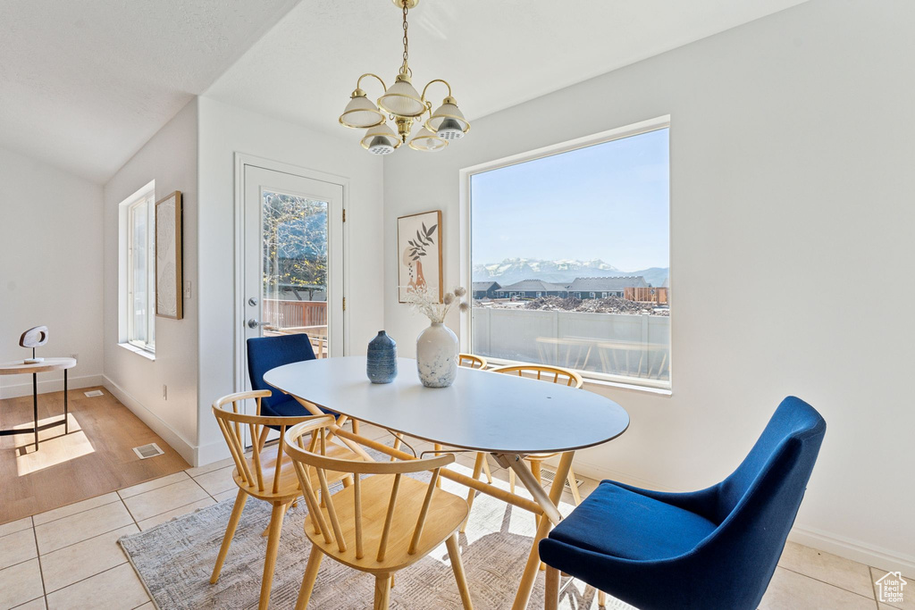 Dining space with light tile patterned floors, a chandelier, baseboards, and a mountain view