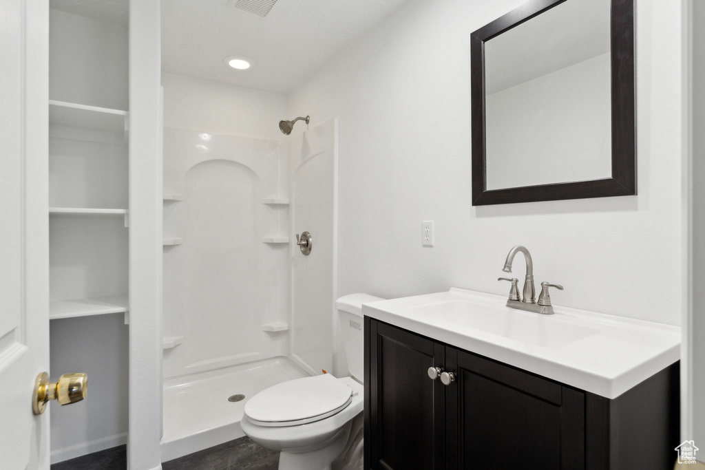 Bathroom with vanity, a shower, and toilet