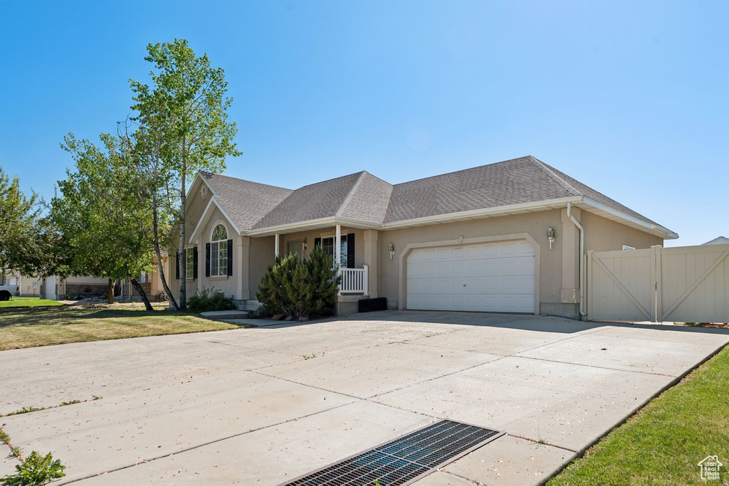 View of front facade with an attached garage, stucco siding, a gate, concrete driveway, and covered porch