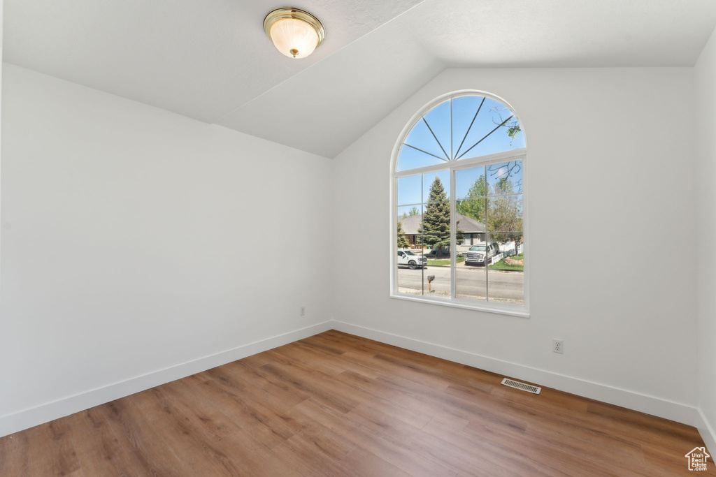 Unfurnished room featuring baseboards, vaulted ceiling, and wood finished floors