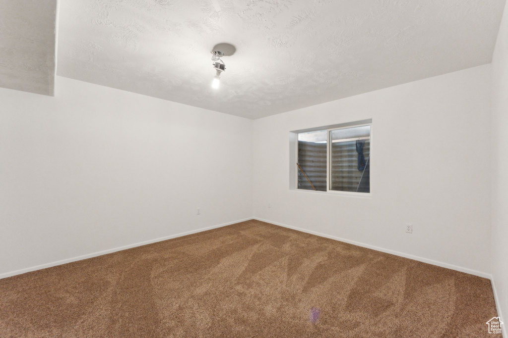 Carpeted spare room featuring baseboards and a textured ceiling