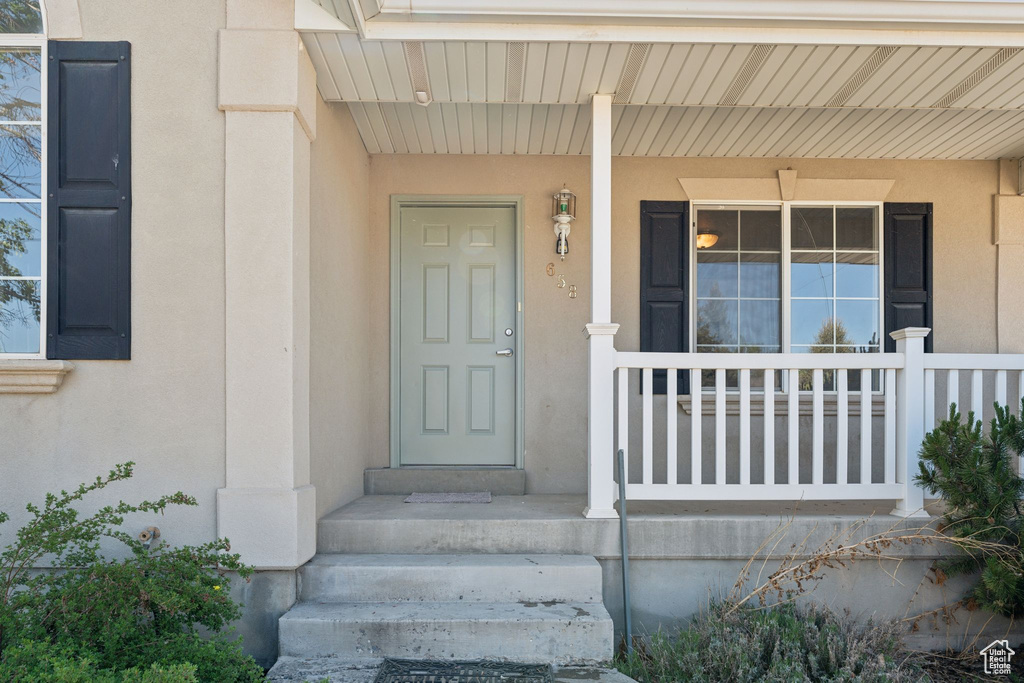 Entrance to property with stucco siding and covered porch