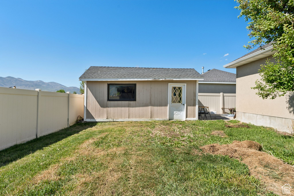 Back of property with an outdoor structure and a mountain view