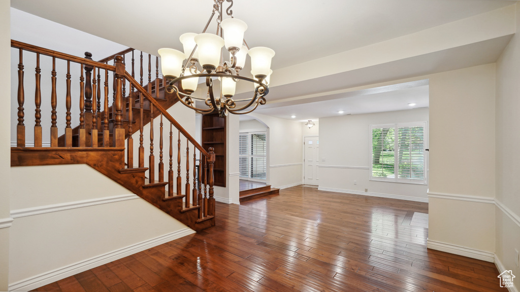 Interior space with a chandelier, wood-type flooring, stairs, baseboards, and recessed lighting