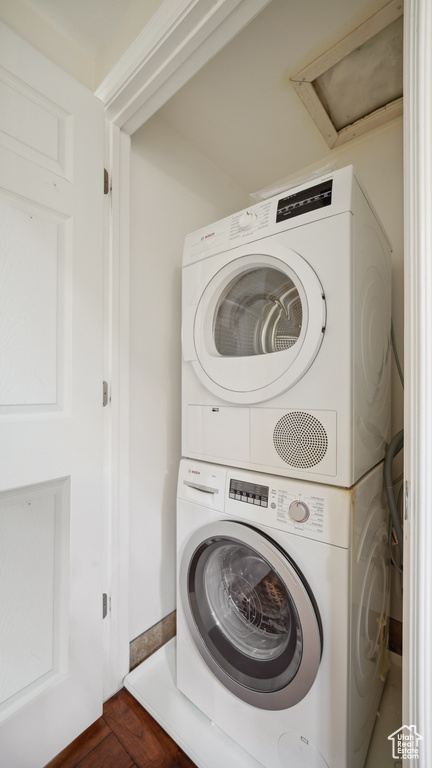 Laundry room with estacked washer and dryer and dark wood-style flooring