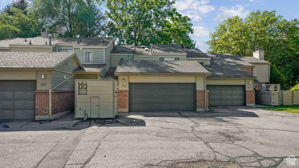 View of property with brick siding, an attached garage, and asphalt driveway
