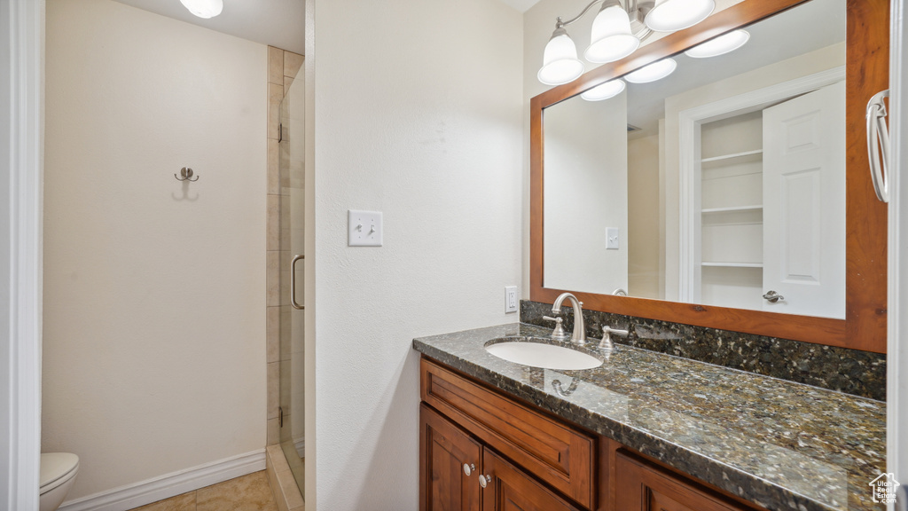 Bathroom with vanity, a stall shower, toilet, and tile patterned flooring