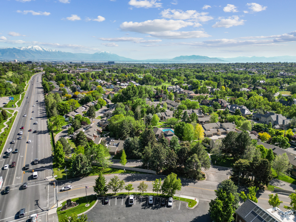 Aerial view of property and surrounding area featuring mountains, nearby suburban area, and a main thoroughfare