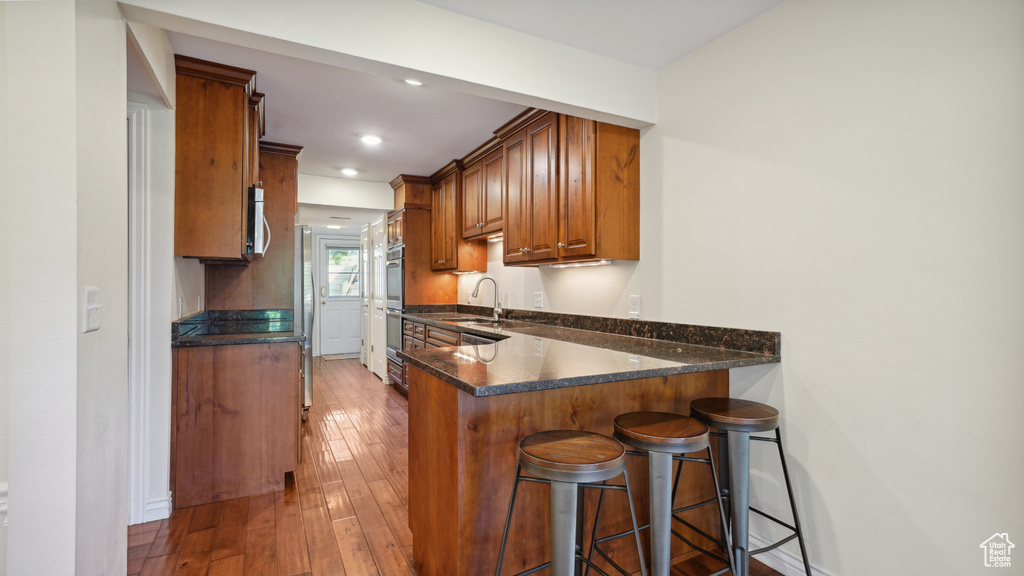 Kitchen featuring brown cabinetry, a breakfast bar, appliances with stainless steel finishes, a peninsula, and a sink