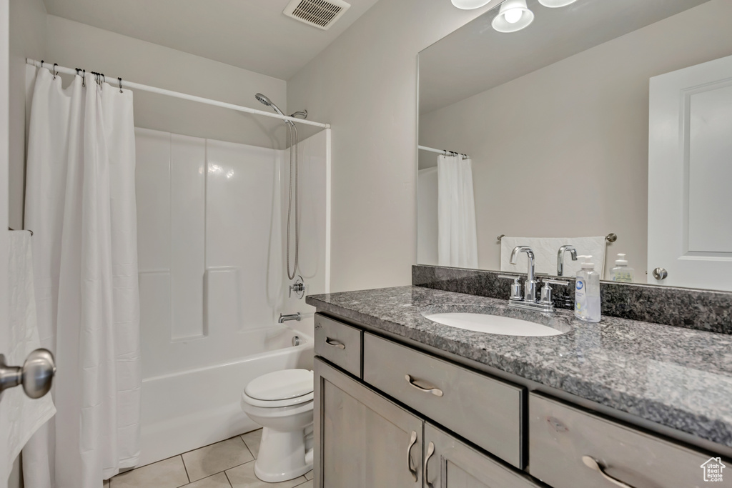 Full bath with vanity, shower / tub combo, tile patterned flooring, and toilet