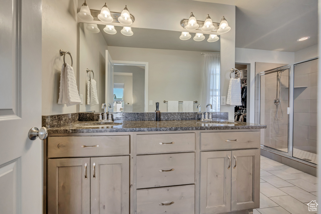 Full bath featuring a shower stall, double vanity, and tile patterned floors